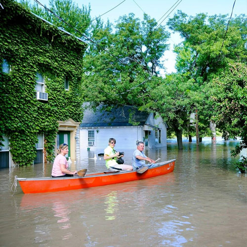three people in a canoe in flooded water